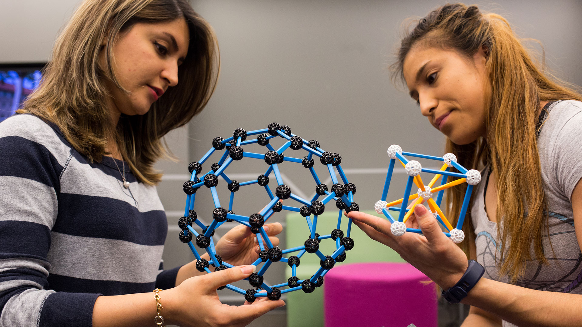 two students examine molecule models in class