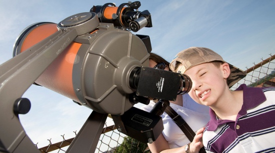 a child looks through the eyepiece of a telescope